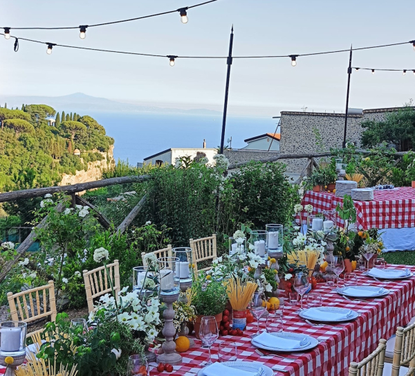 Tavola allestita con colori vivaci e decorazioni mediterranee per una cena conviviale in Costiera Amalfitana